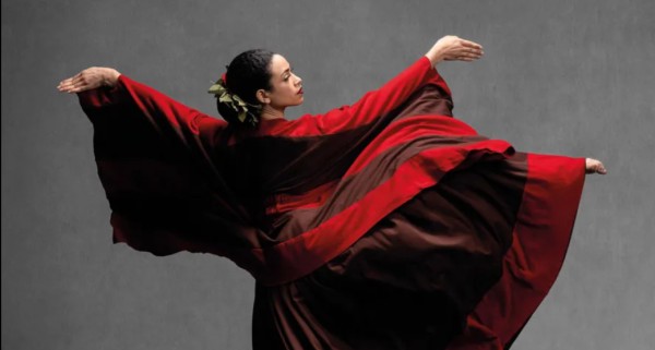 A woman dancing wearing a red, flowy dress.