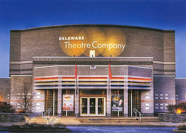 A brick building with three doors, with white text stating 'Delaware Theatre Company' on the front.