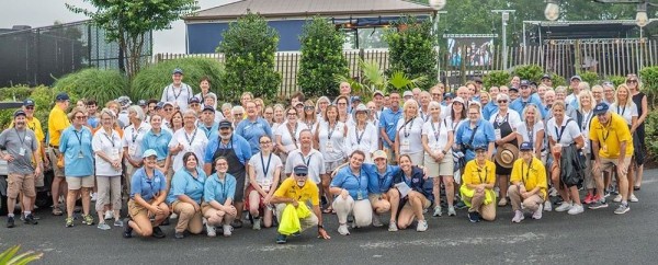 A large group of people in white, blue, and yellow, outside on the street in front of an outdoor venue.